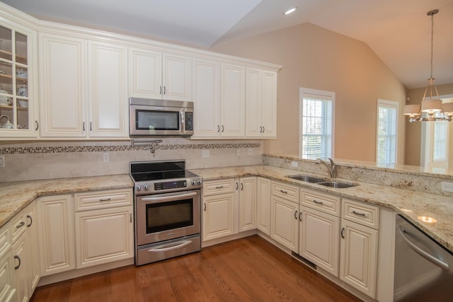 kitchen featuring appliances with stainless steel finishes, a sink, a chandelier, wood finished floors, and lofted ceiling