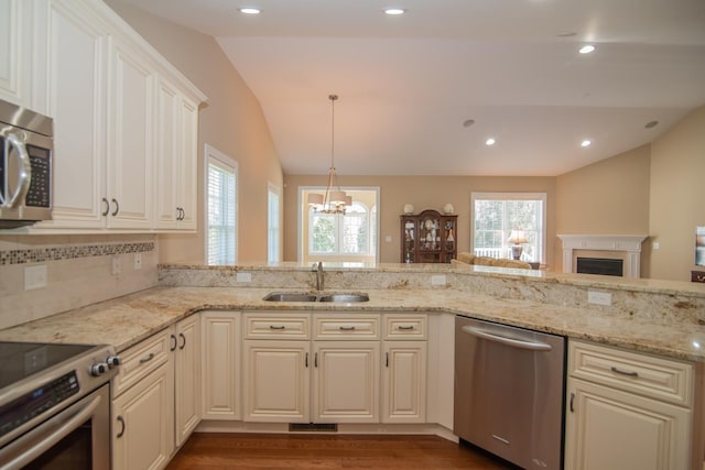 kitchen featuring light stone counters, an inviting chandelier, a sink, stainless steel appliances, and lofted ceiling