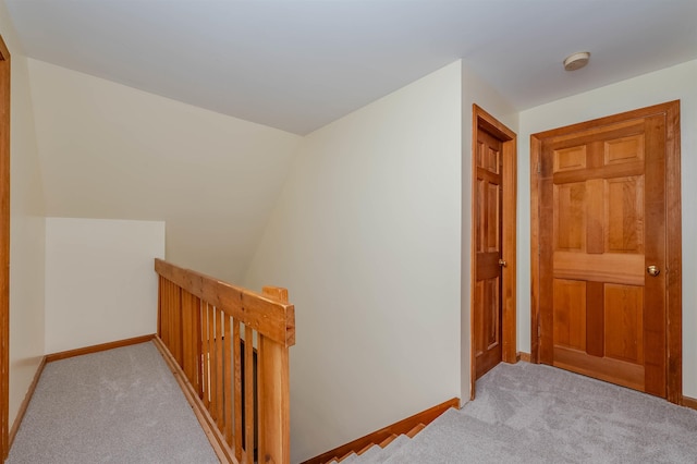 hall with carpet floors, baseboards, and an upstairs landing