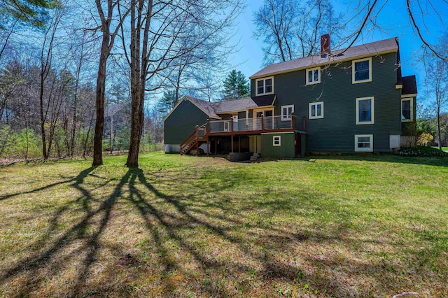 rear view of house featuring a lawn, a wooden deck, a chimney, and stairs