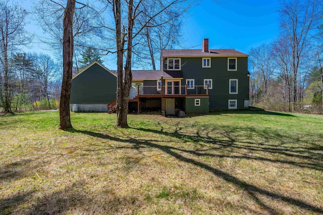 rear view of house featuring a lawn, a wooden deck, and a chimney