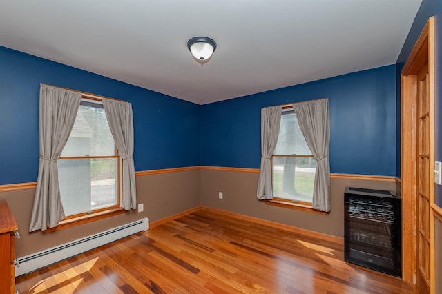 empty room with baseboards, a baseboard heating unit, wood finished floors, and heating unit