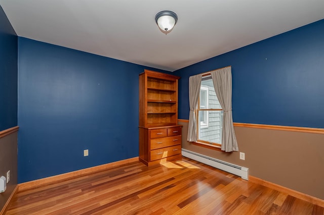 unfurnished room with baseboards, light wood-type flooring, and a baseboard radiator