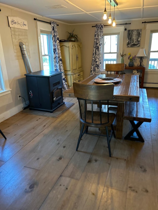 dining space with a wood stove, light wood-style flooring, and a baseboard radiator