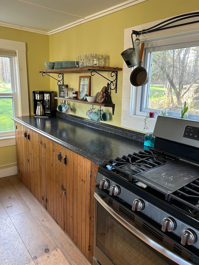 kitchen with crown molding, dark countertops, open shelves, light wood finished floors, and stainless steel range with gas cooktop