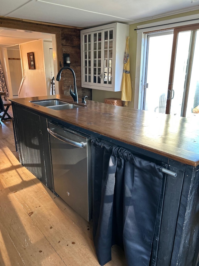 kitchen with light wood-style floors, dishwasher, a sink, glass insert cabinets, and butcher block countertops