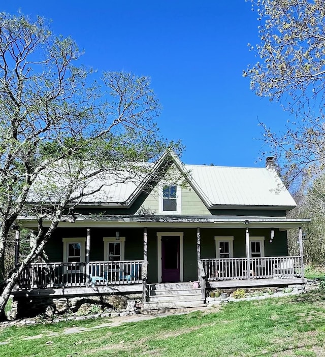 country-style home with a porch, a front yard, and a chimney