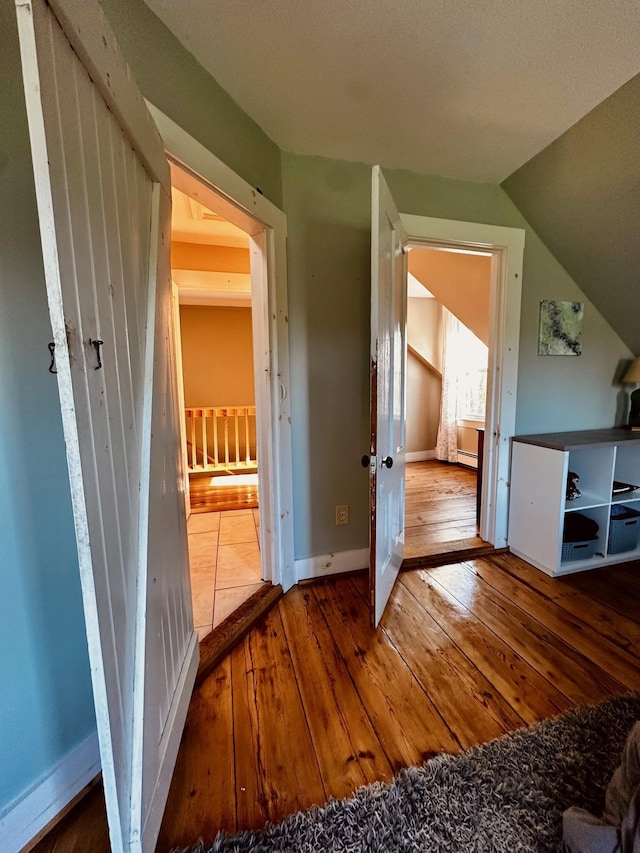 additional living space with baseboards, vaulted ceiling, and hardwood / wood-style floors