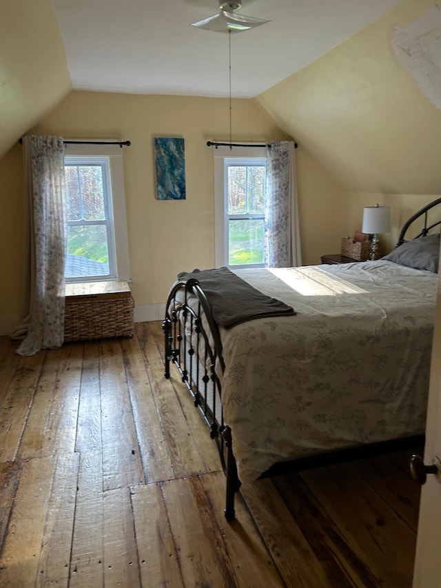 bedroom with baseboards, multiple windows, lofted ceiling, and hardwood / wood-style floors