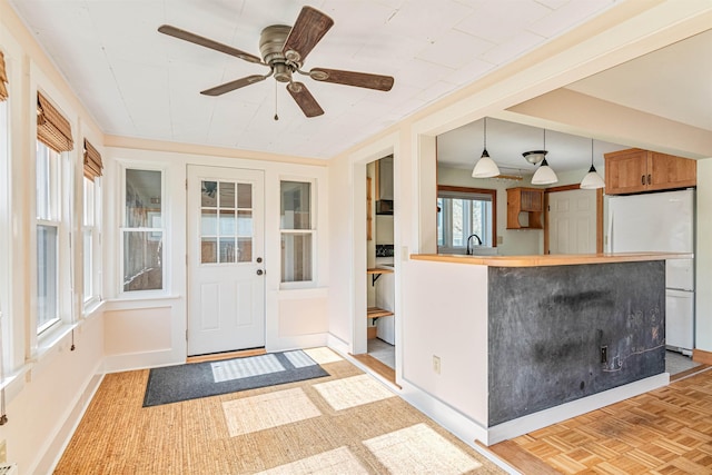interior space featuring a sink, baseboards, ceiling fan, and freestanding refrigerator