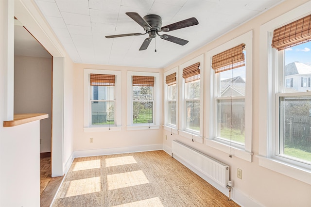 unfurnished sunroom with baseboards, radiator, and a wealth of natural light