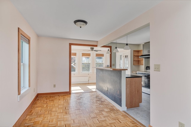 kitchen featuring dark countertops, hanging light fixtures, baseboards, under cabinet range hood, and white electric range