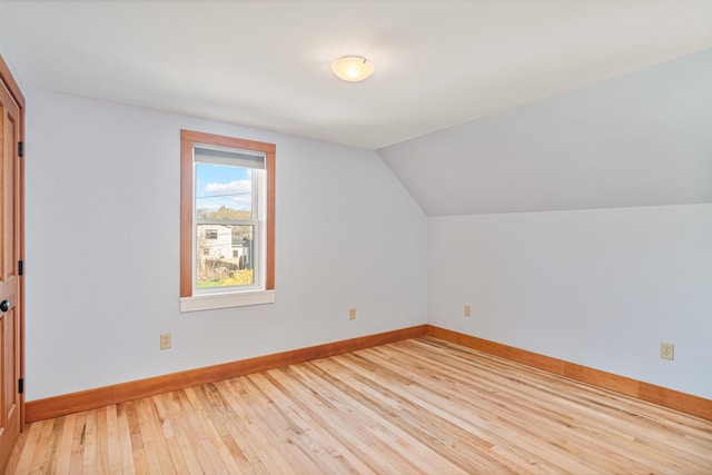 additional living space featuring light wood-type flooring, baseboards, and vaulted ceiling