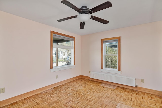 unfurnished room featuring baseboards, ceiling fan, and radiator heating unit