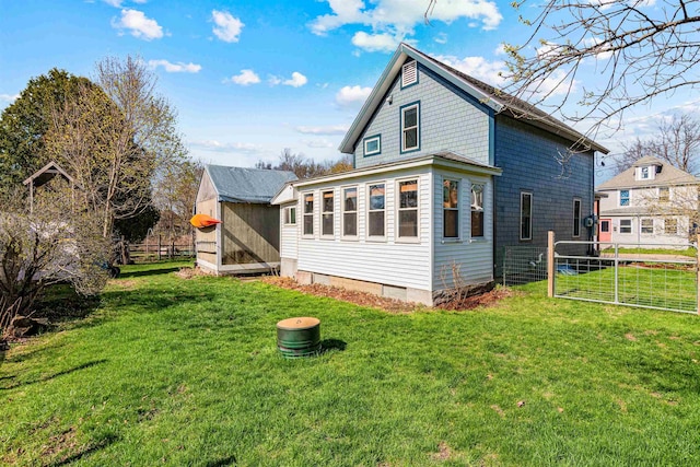 back of house featuring a lawn, fence, and an outbuilding