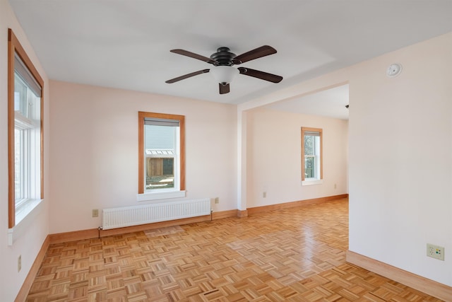spare room with radiator, baseboards, and a ceiling fan