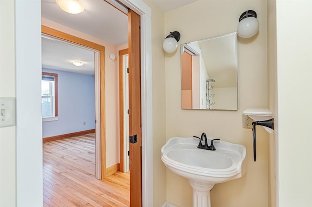 bathroom with baseboards, a sink, and hardwood / wood-style flooring