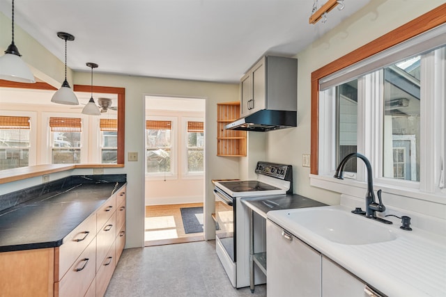 kitchen with white electric stove, decorative light fixtures, dark countertops, a sink, and under cabinet range hood
