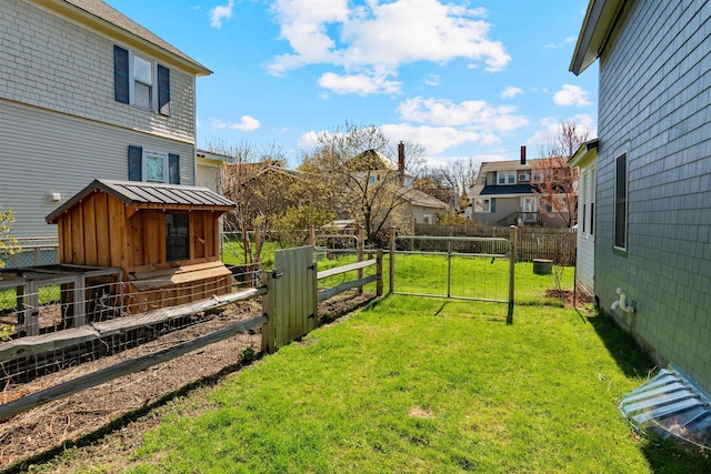 view of yard featuring an outdoor structure, a gate, fence, and a residential view