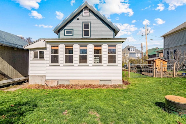 rear view of house with a storage unit, an outdoor structure, a lawn, and fence