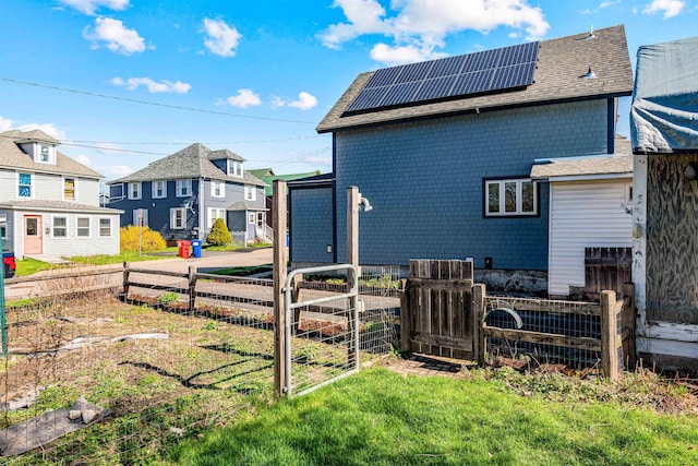 view of property exterior with a residential view, a gate, fence, roof mounted solar panels, and a yard
