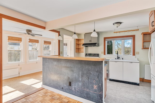 kitchen featuring a ceiling fan, pendant lighting, stove, radiator, and under cabinet range hood