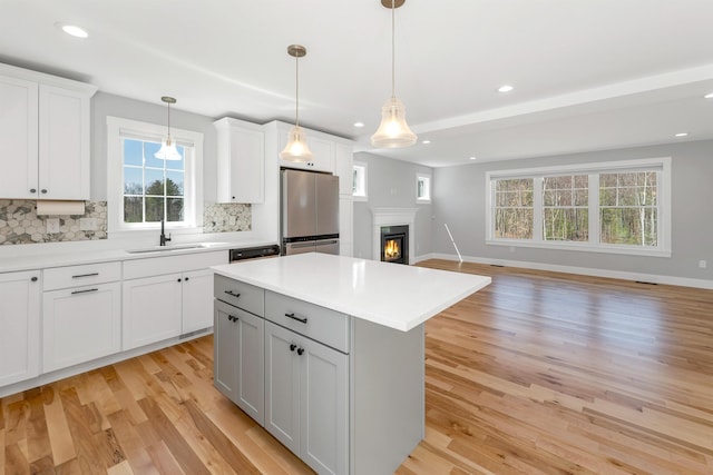 kitchen featuring backsplash, a sink, freestanding refrigerator, light wood finished floors, and open floor plan
