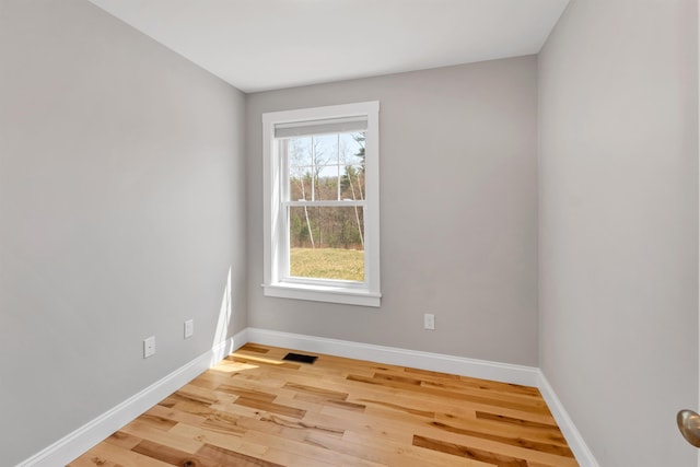 spare room with baseboards, light wood-type flooring, and visible vents