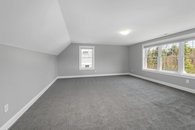 bonus room with baseboards, dark carpet, and lofted ceiling