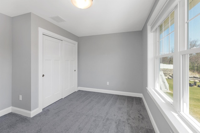 unfurnished bedroom featuring baseboards, multiple windows, and dark colored carpet