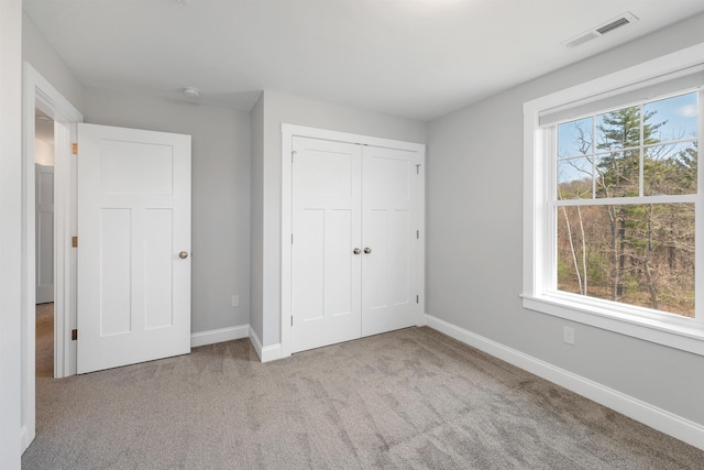 unfurnished bedroom featuring baseboards, visible vents, carpet, and a closet
