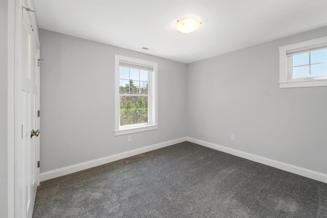 empty room with baseboards, visible vents, and dark carpet