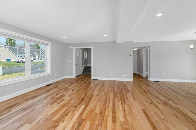unfurnished living room with stairs, baseboards, visible vents, and light wood-style floors