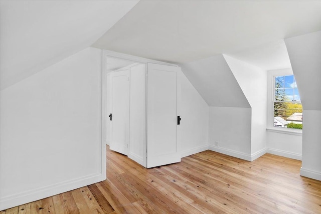 bonus room with light wood-style floors, baseboards, and lofted ceiling