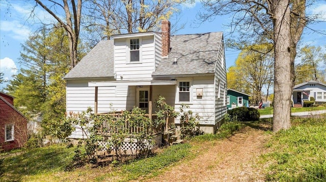 exterior space with a shingled roof and a chimney