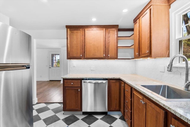 kitchen featuring a healthy amount of sunlight, appliances with stainless steel finishes, open shelves, a sink, and light floors