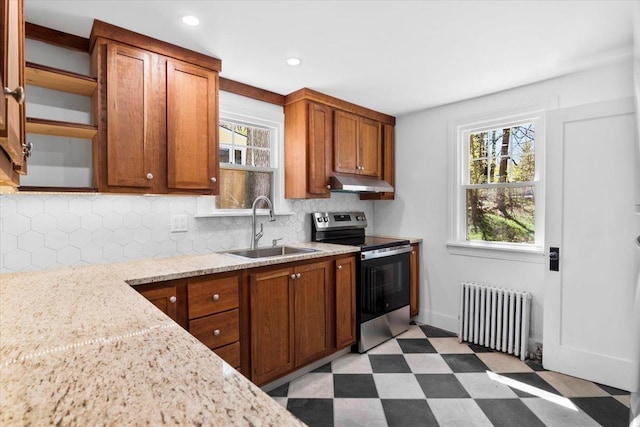 kitchen with stainless steel range with electric stovetop, light floors, radiator heating unit, under cabinet range hood, and a sink