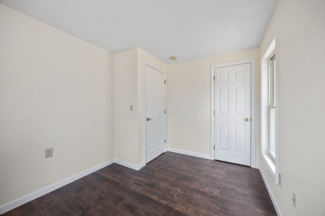 unfurnished bedroom featuring baseboards and dark wood-type flooring