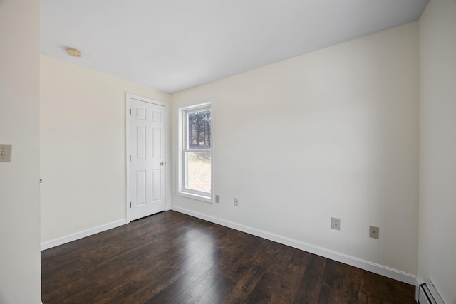 empty room featuring dark wood-style flooring, baseboards, and baseboard heating