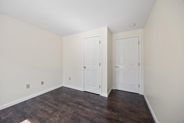 unfurnished bedroom with baseboards and dark wood finished floors