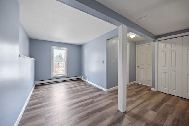 below grade area featuring baseboards, a baseboard heating unit, and wood finished floors
