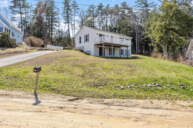 view of front of home with a wooden deck, driveway, and a front lawn