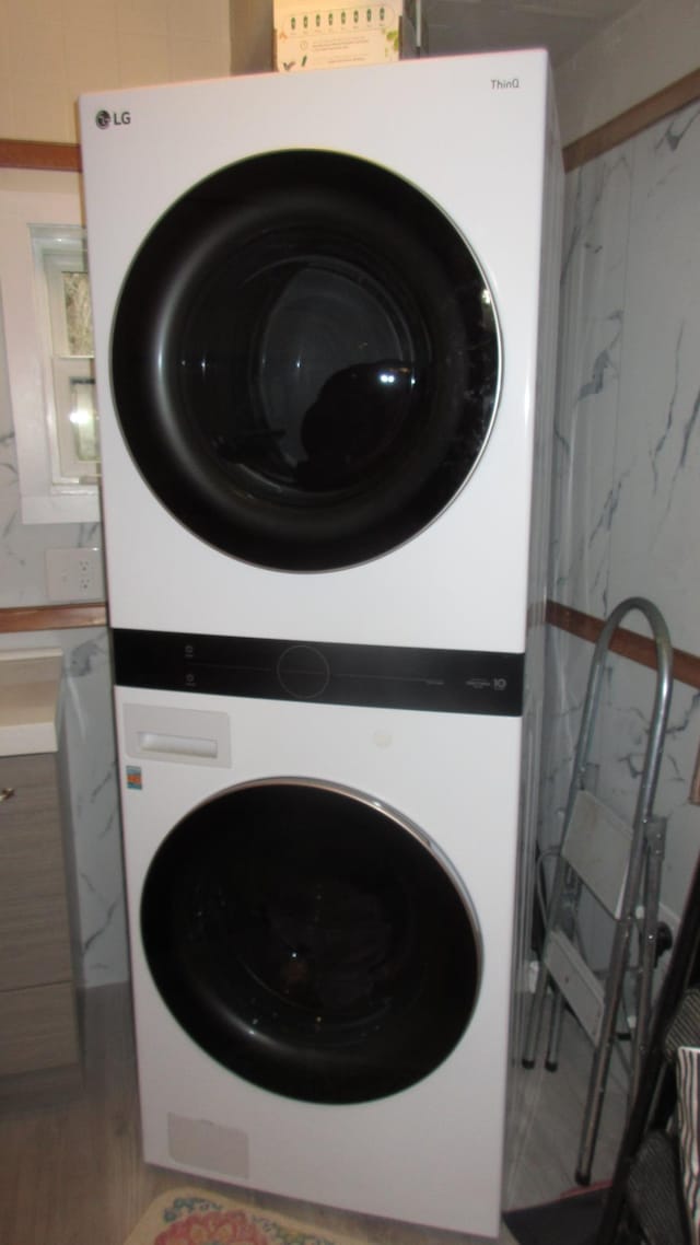 clothes washing area with laundry area and stacked washing maching and dryer