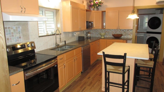 kitchen featuring stacked washer / drying machine, a sink, stainless steel appliances, decorative backsplash, and under cabinet range hood
