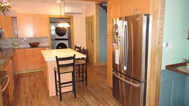 kitchen featuring a kitchen breakfast bar, light wood-type flooring, a wall mounted air conditioner, freestanding refrigerator, and stacked washer and clothes dryer