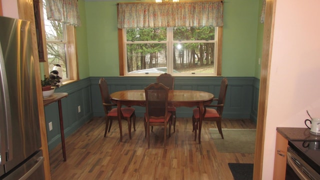 dining room with plenty of natural light, wood finished floors, and a wainscoted wall