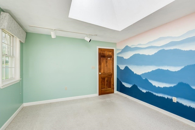 unfurnished room with track lighting, carpet floors, and baseboards