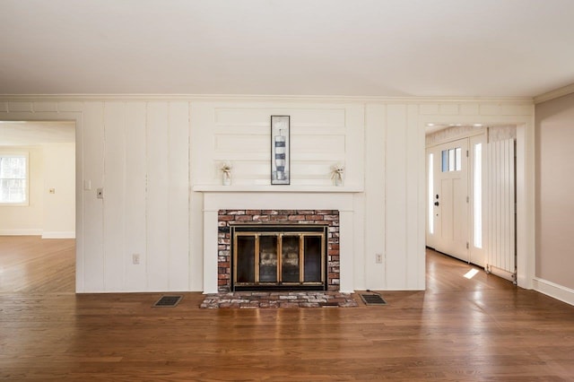 unfurnished living room featuring baseboards, ornamental molding, wood finished floors, and visible vents