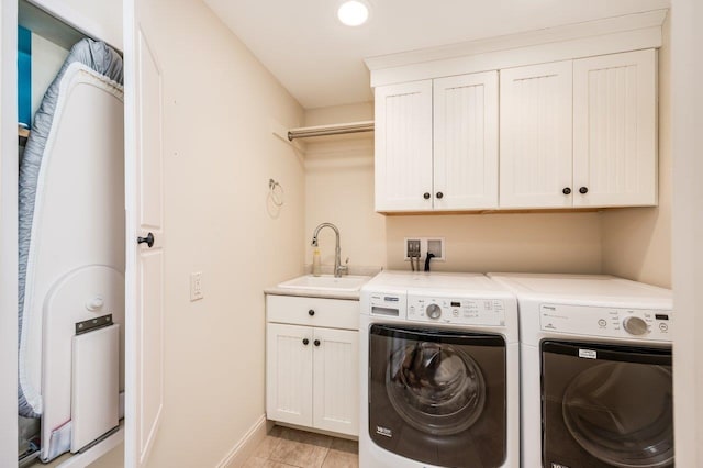 clothes washing area featuring cabinet space, a sink, baseboards, light tile patterned floors, and washer and dryer