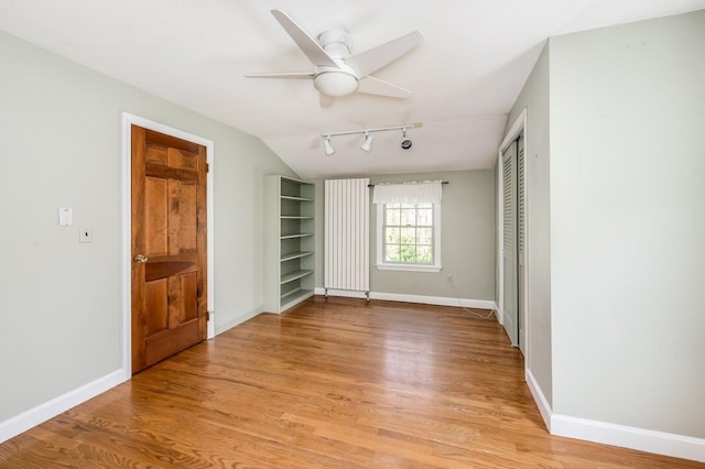 unfurnished bedroom featuring light wood-type flooring, baseboards, lofted ceiling, and a closet